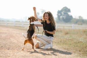 excited woman playing with a dog in a field