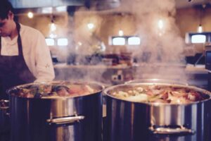 man cooking soup in big pots